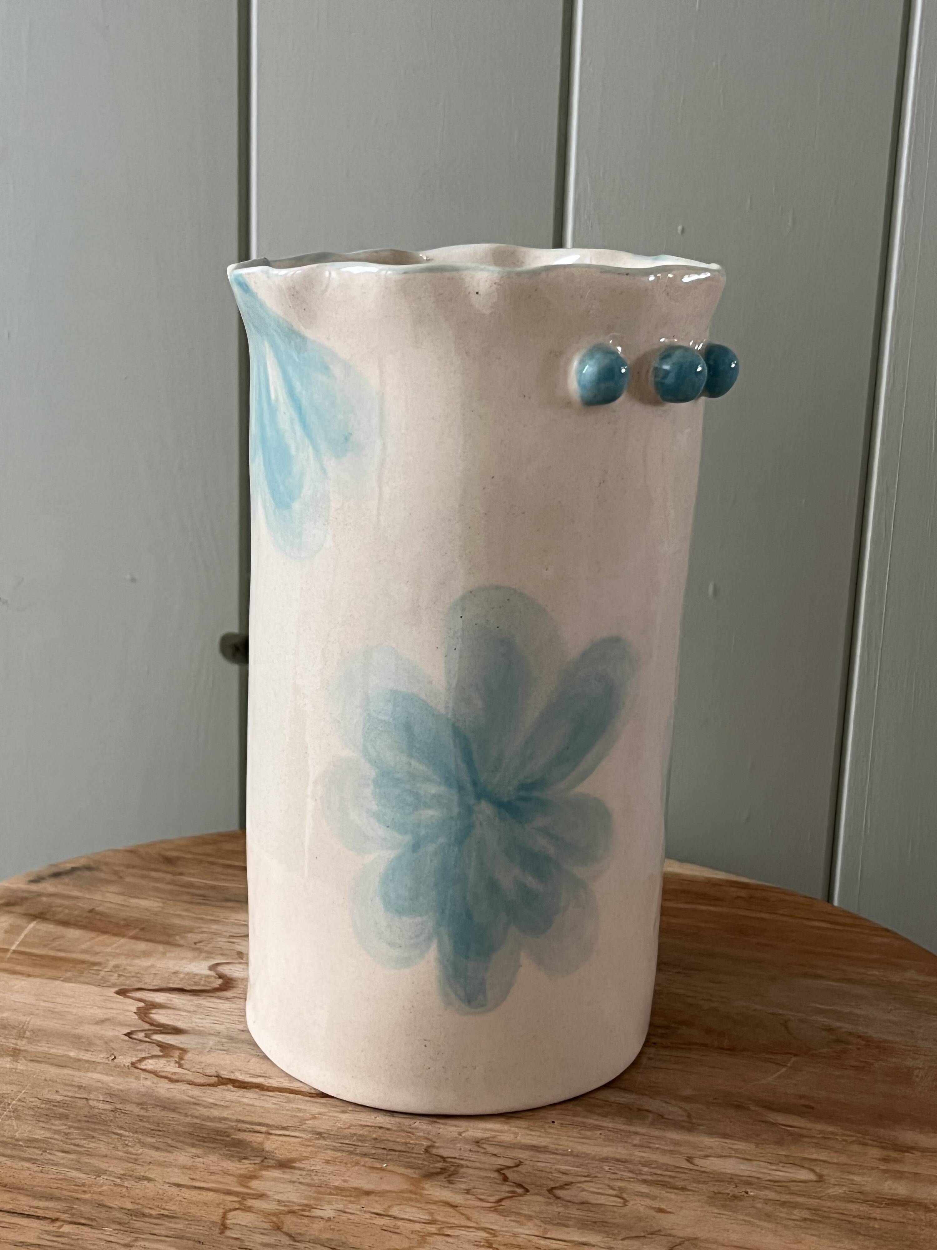 Stoneware vase decorated with flowers in a watercolour style.