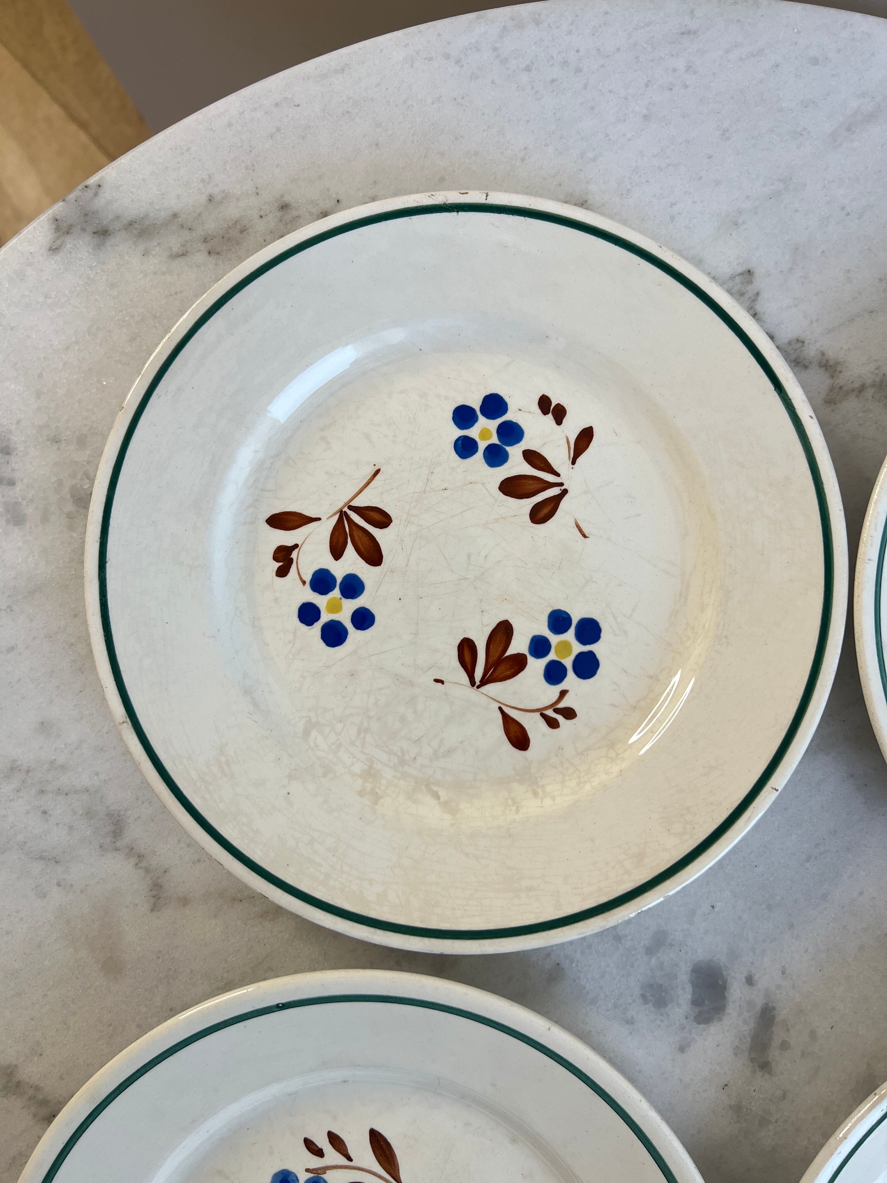 Set of 4 small flat plates with floral designs.