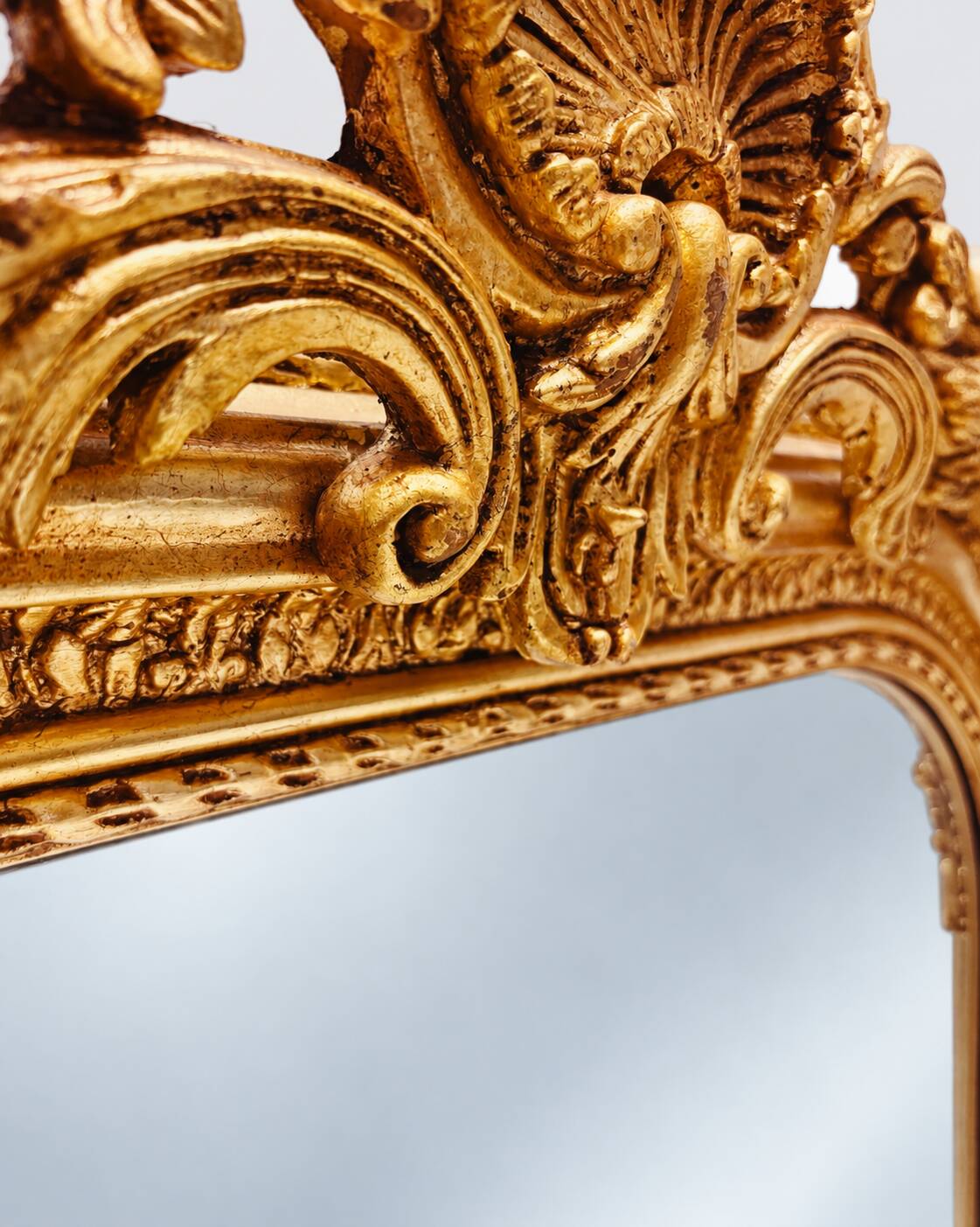 Grand miroir baroque en or avec un crête orné.