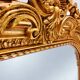 Grand miroir baroque en or avec un crête orné.