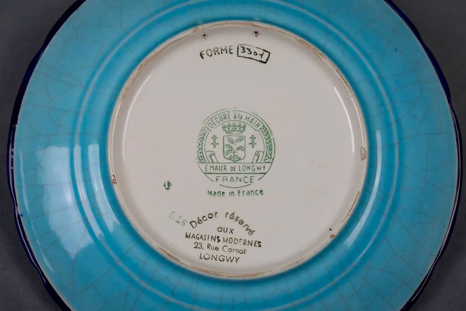 Longwy plate with polychrome enamels, decorated with the "City of Iron" motif.