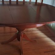 Round solid walnut table with central leg from the 1950s with extensions.
