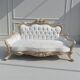 A white and gold tufted beech wood sofa in Louis XV style.