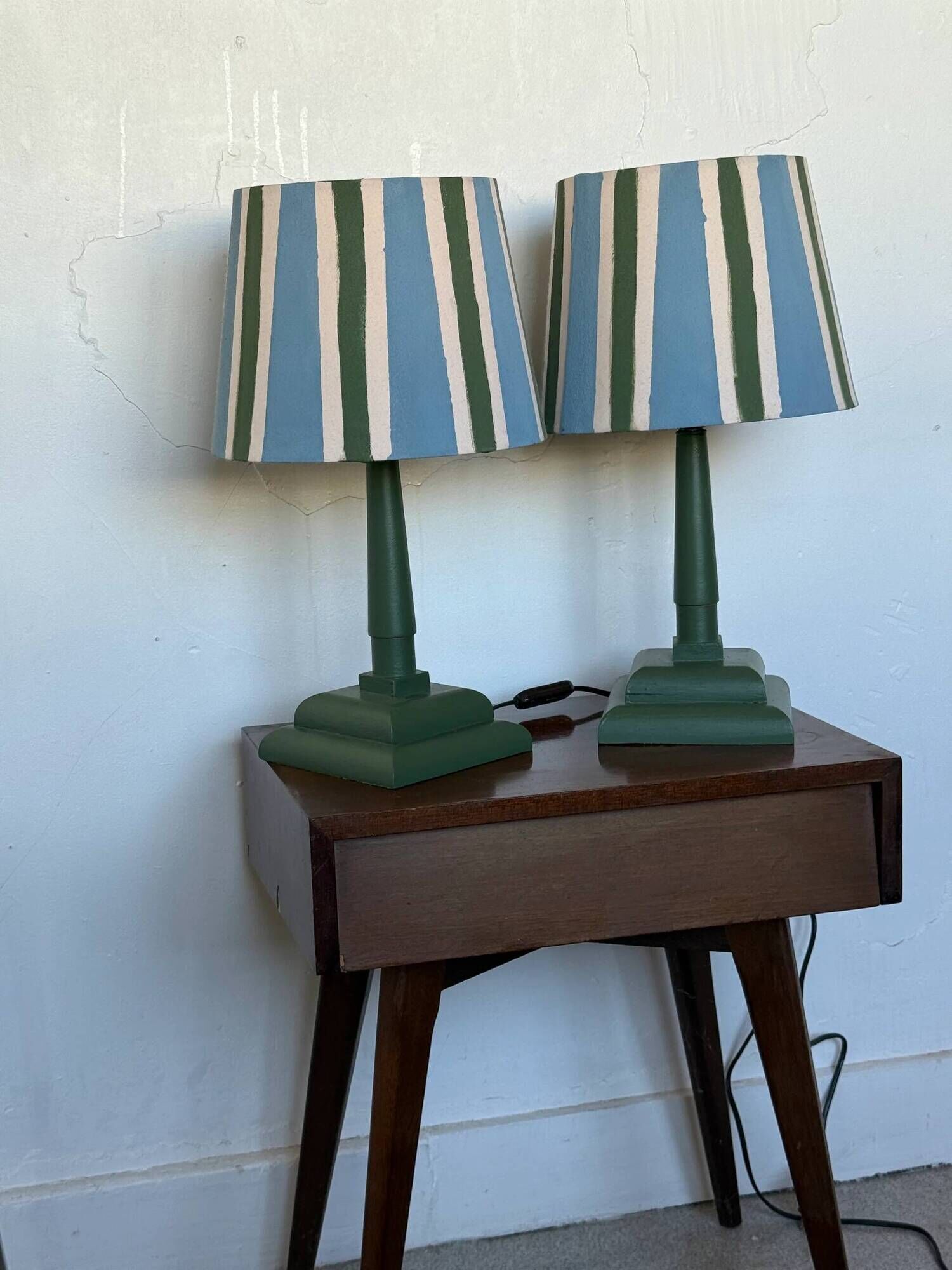 Pair of vintage wooden lamps with their striped beige, blue, and green shades.