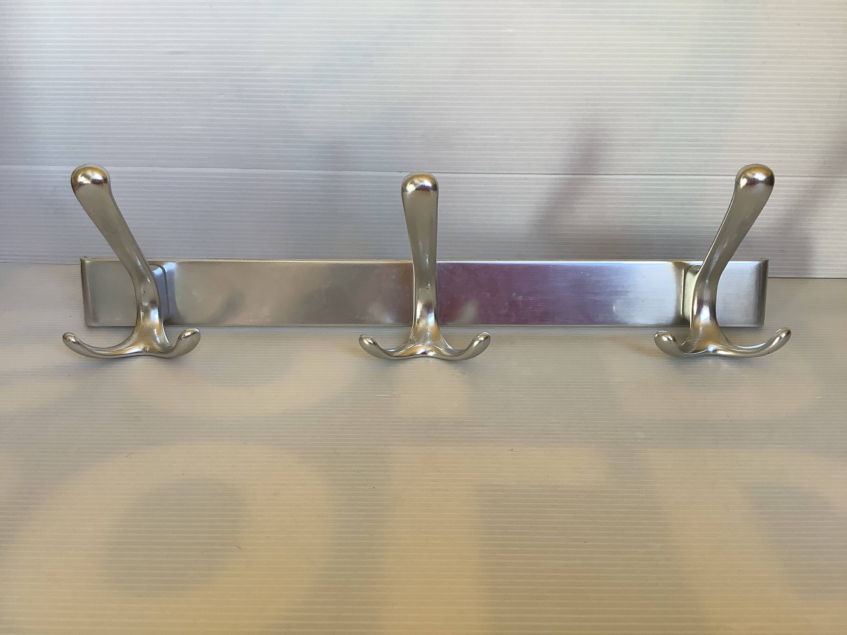 Stainless steel coat rack with three double hooks.