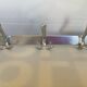 Stainless steel coat rack with three double hooks.