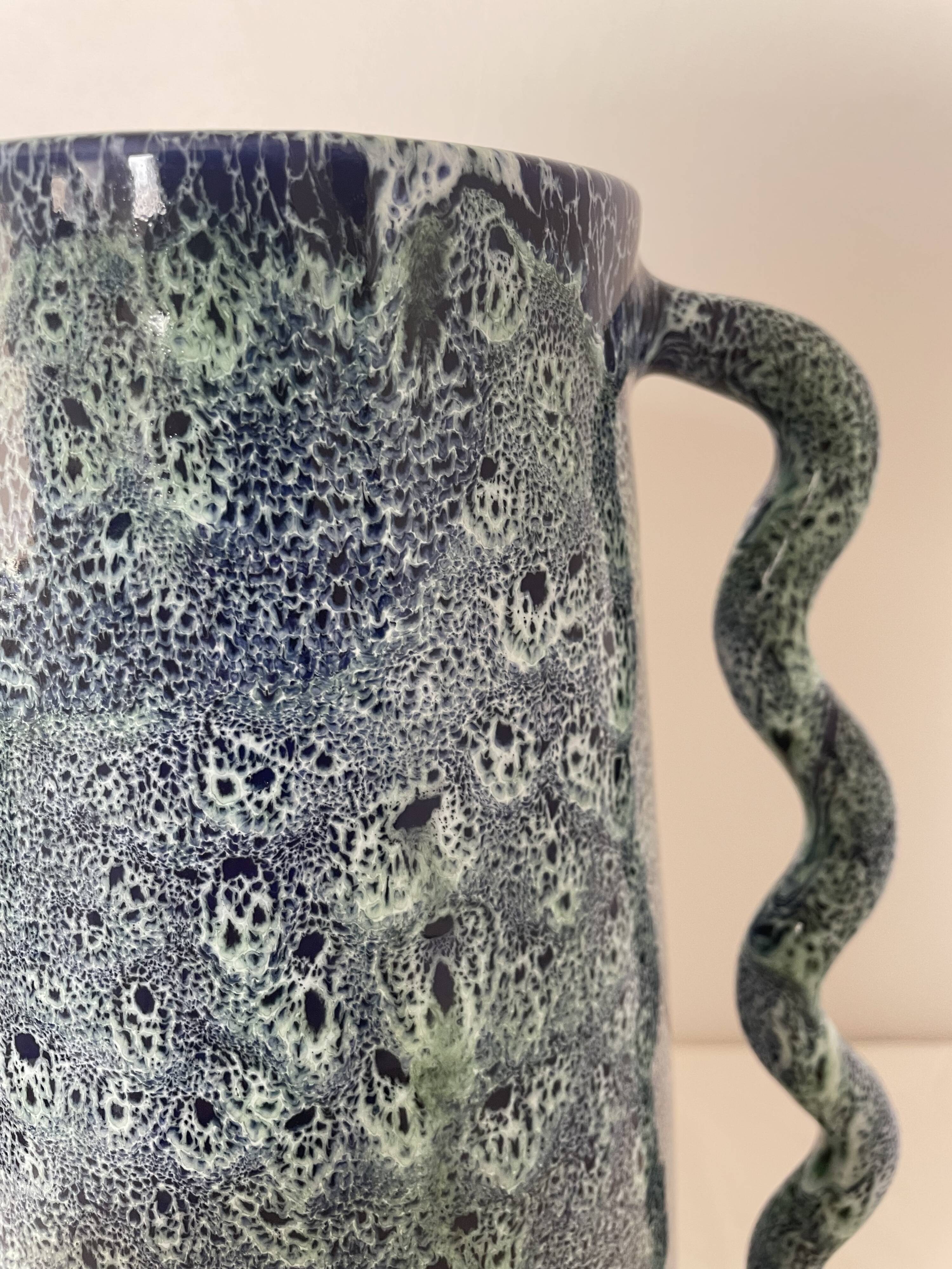 Blue-green ceramic vase with abstract wavy handles