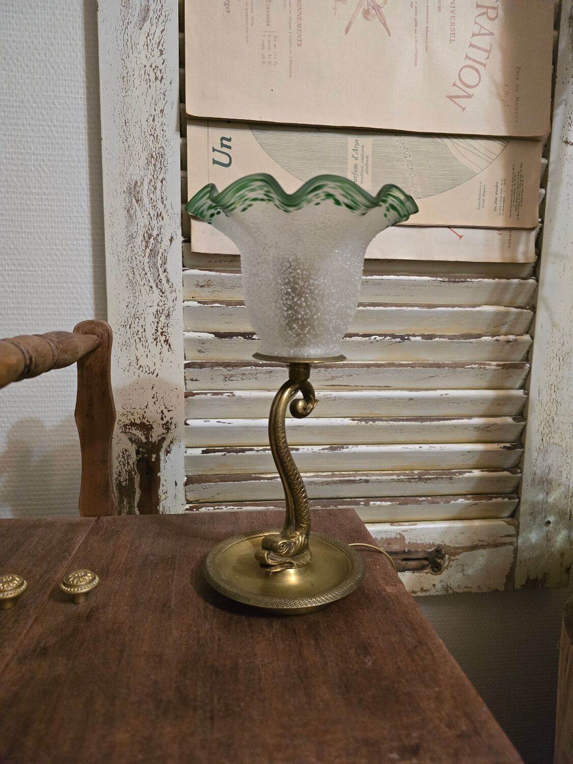 Small table lamp with a brass fish base and a tulip shade with green edges.