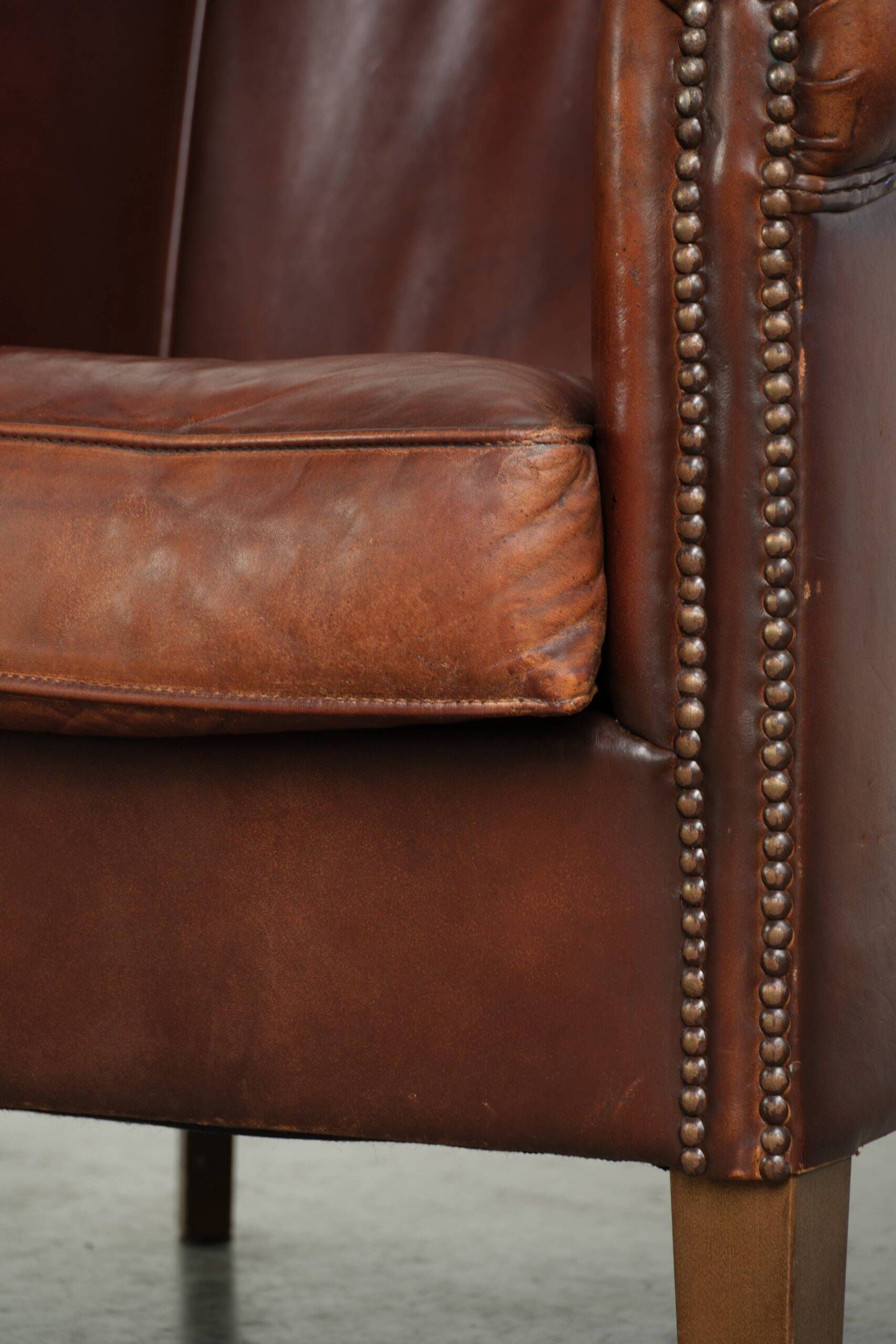 Characterful sheepskin club armchair in a dark cognac colour in English style