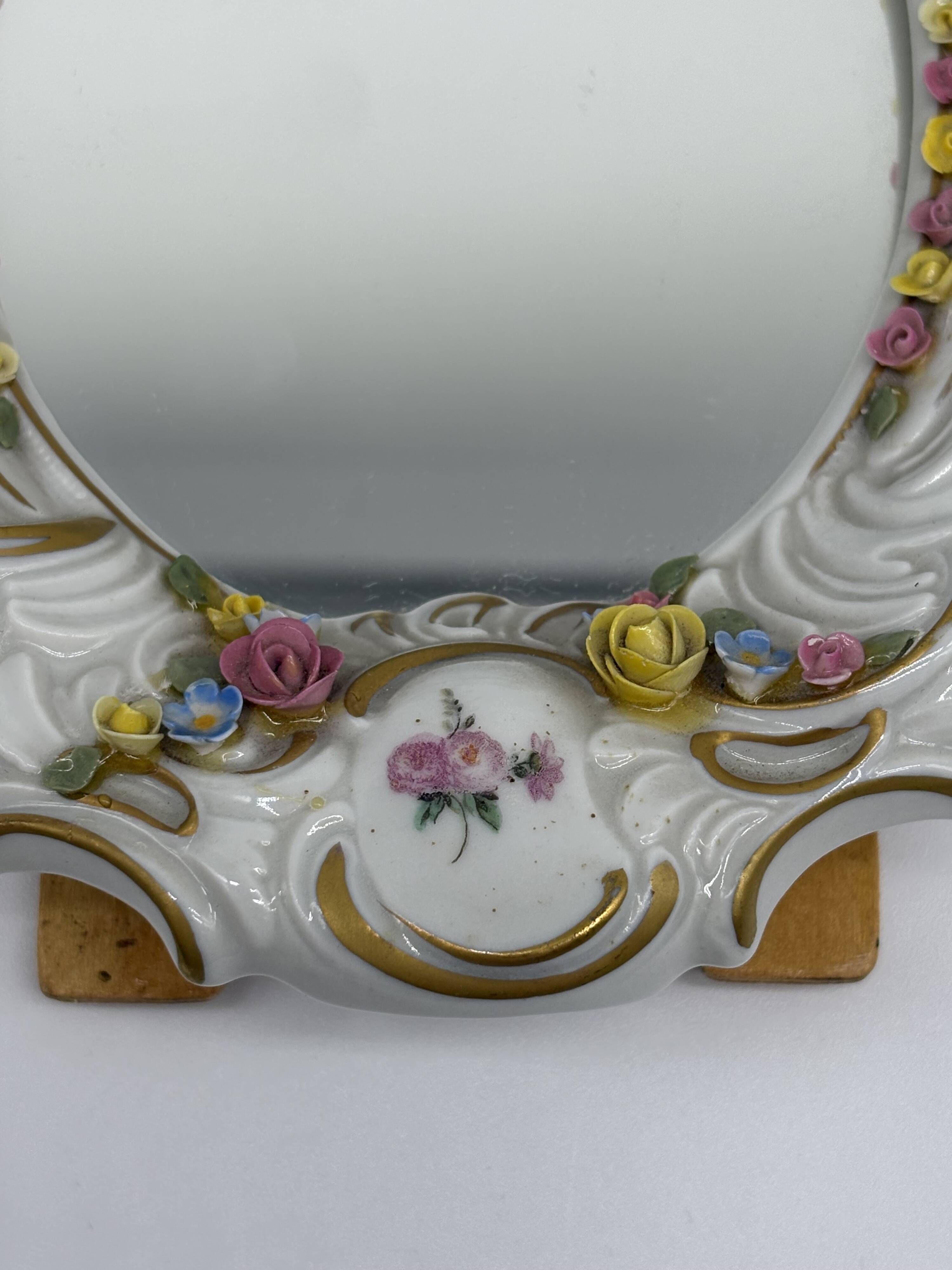 Antique porcelain mirror from Dresden with relief flowers and rococo decoration.