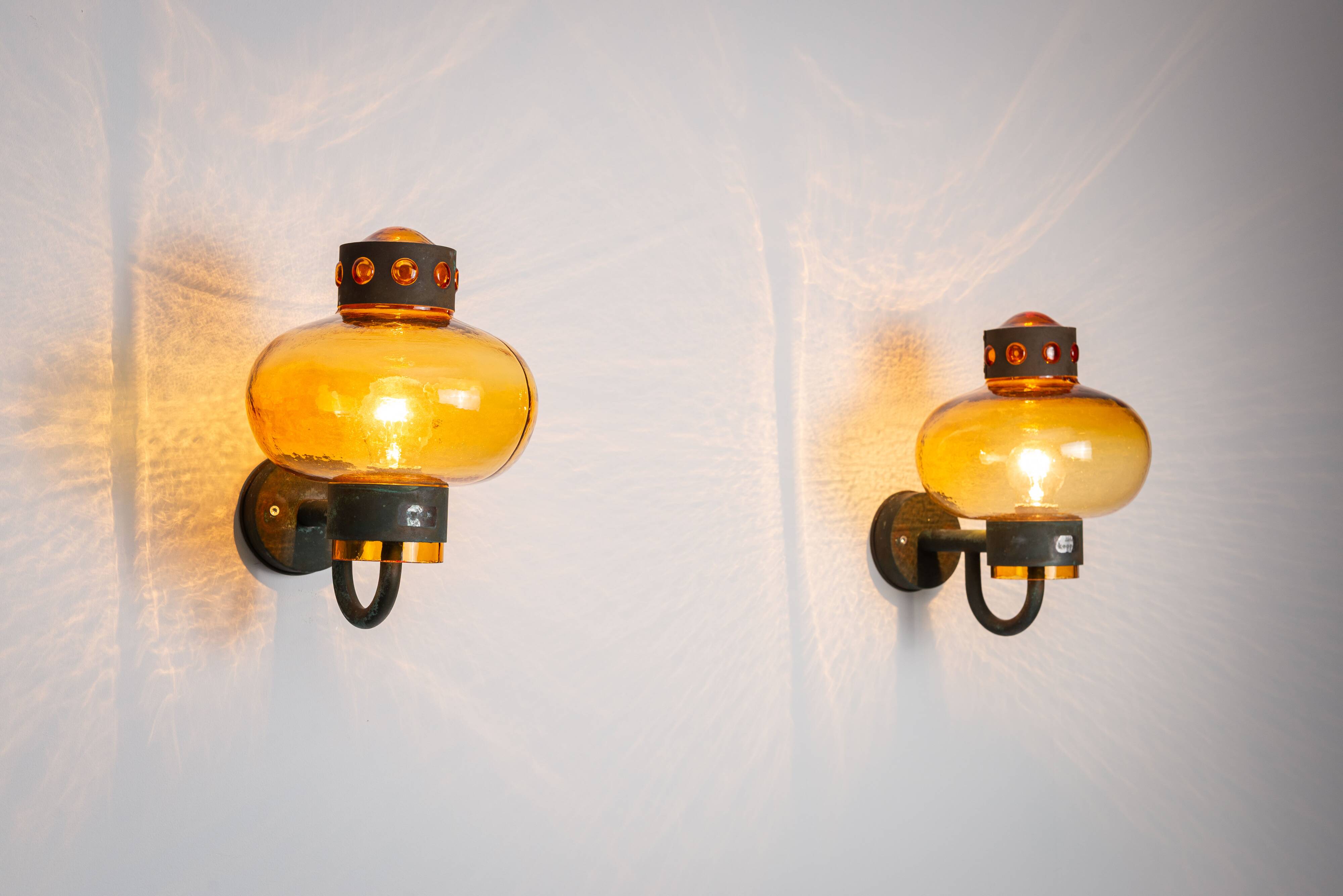Pair of brass wall lamps with decorated amber coloured shades