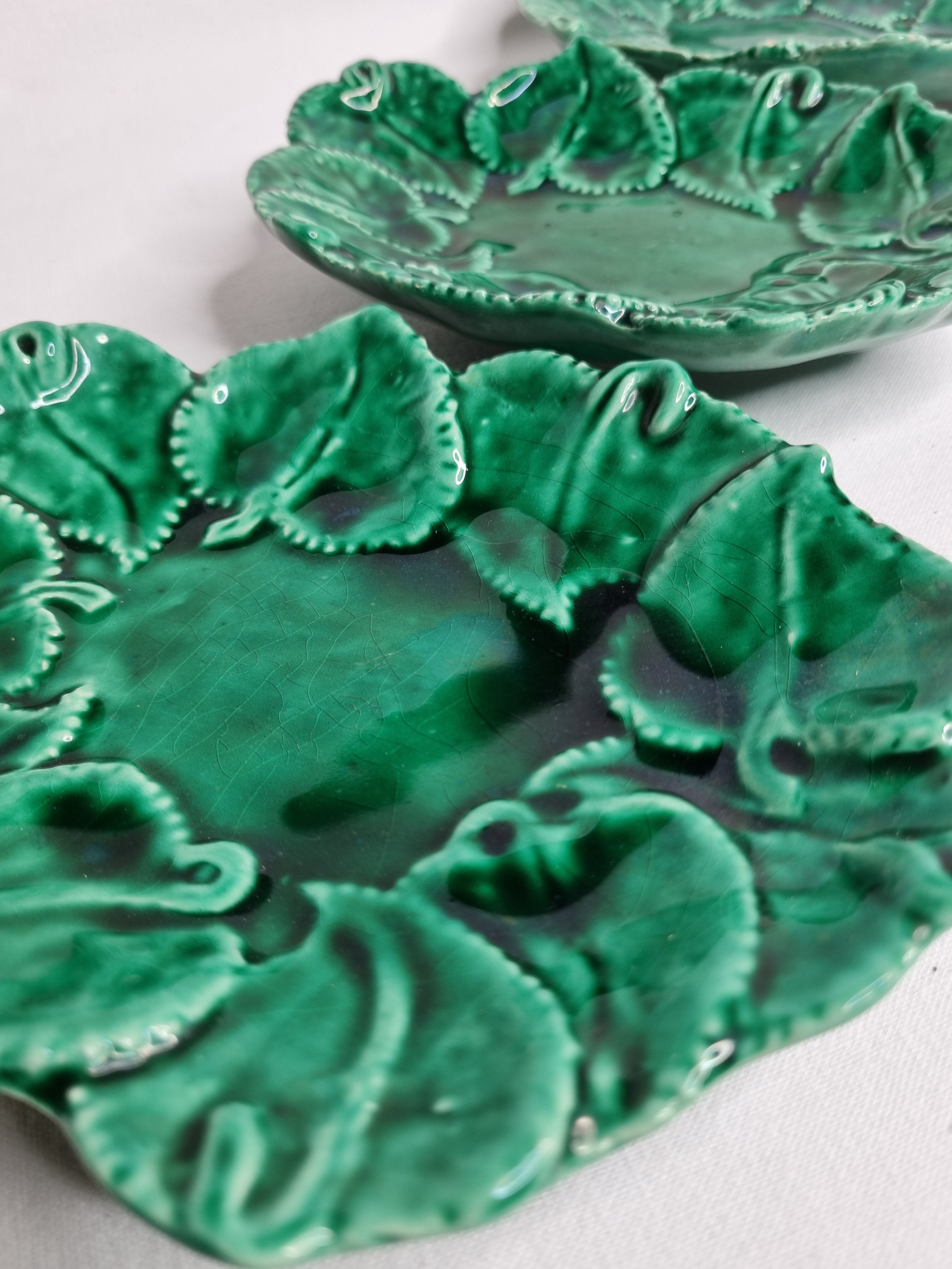 Set of three enamelled, emerald green, leaf-decorated faent cups
