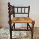 Old wooden turned spindle fireside chair with a straw seat.