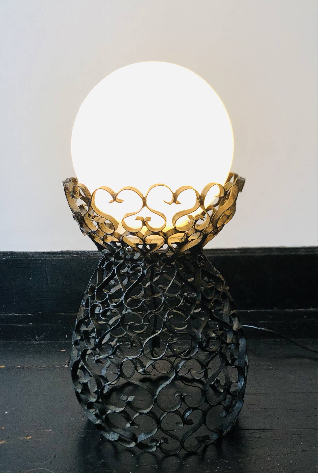 Handcrafted wrought iron lamp with a white opaline globe.
