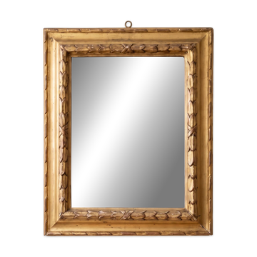 Antique wall mirror with a carved gilded frame featuring leaf motifs.