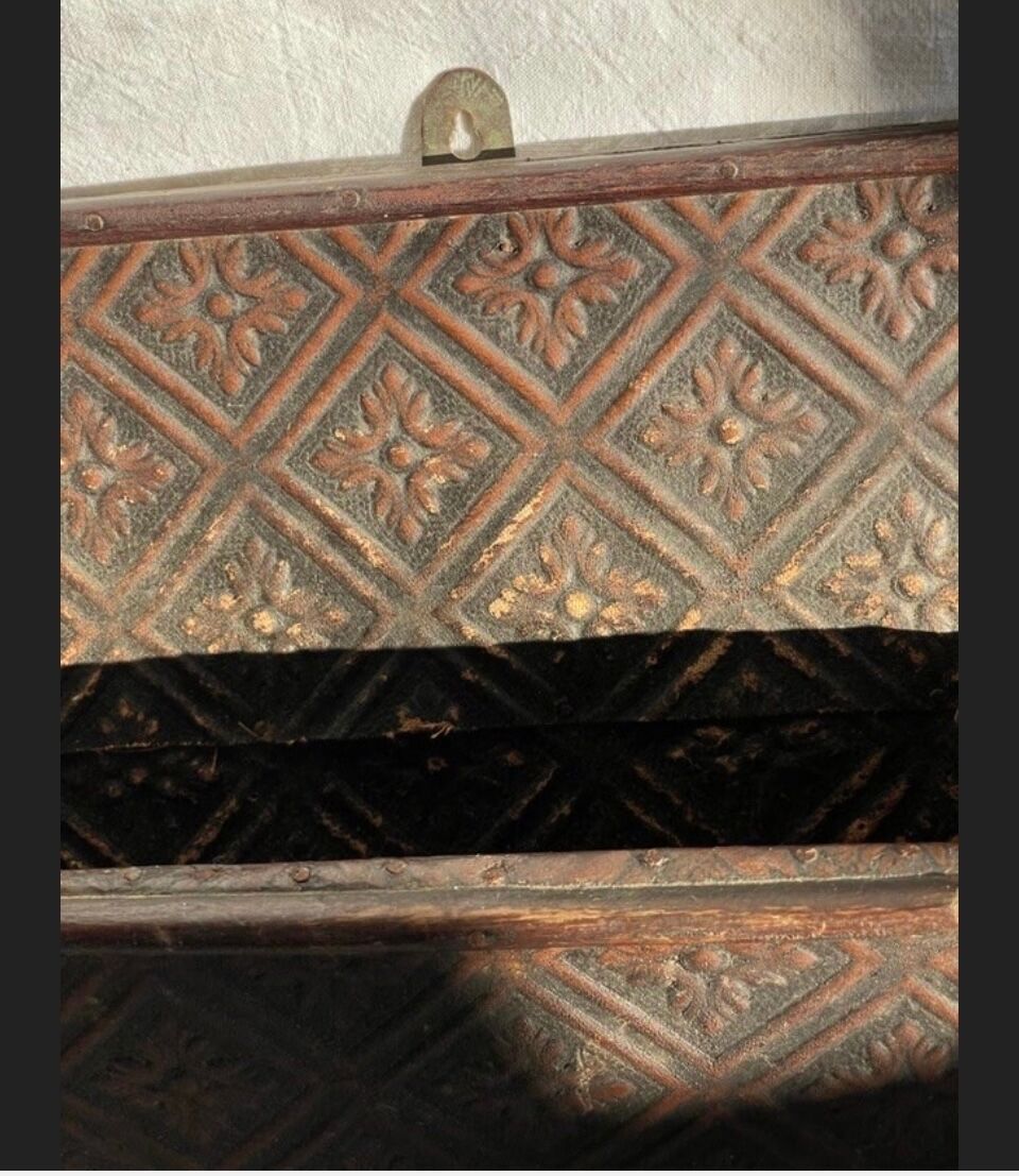 Hammered leather wall mail holder on wood.