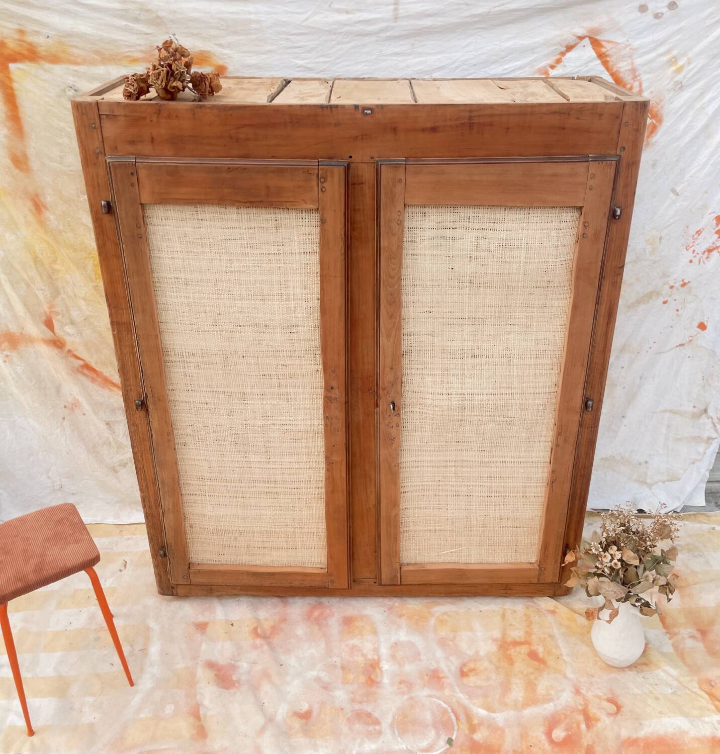 Low cabinet in raw wood and woven raffia.