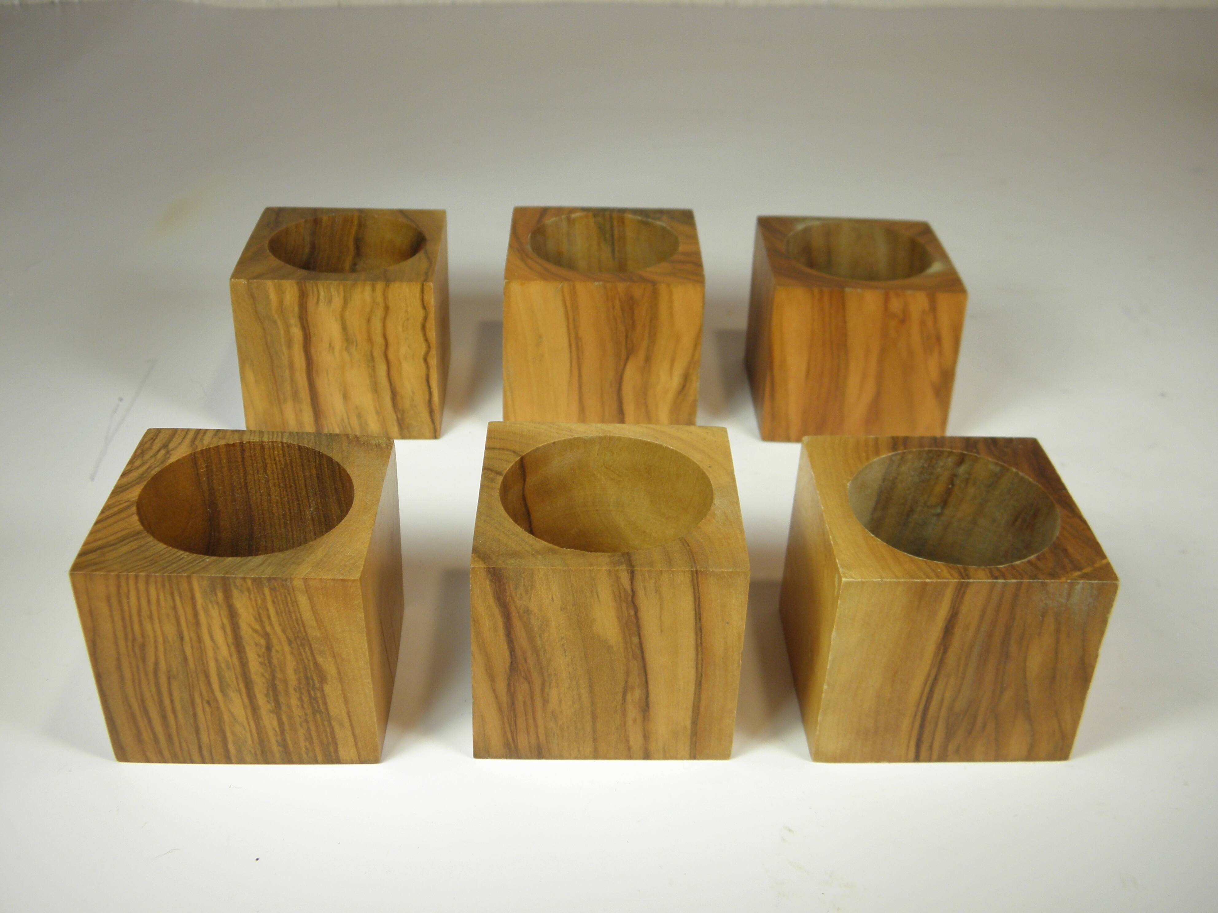 Six egg cups on a wooden tray.
