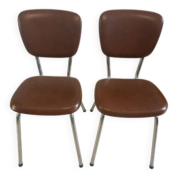 Two brown faux leather chairs.