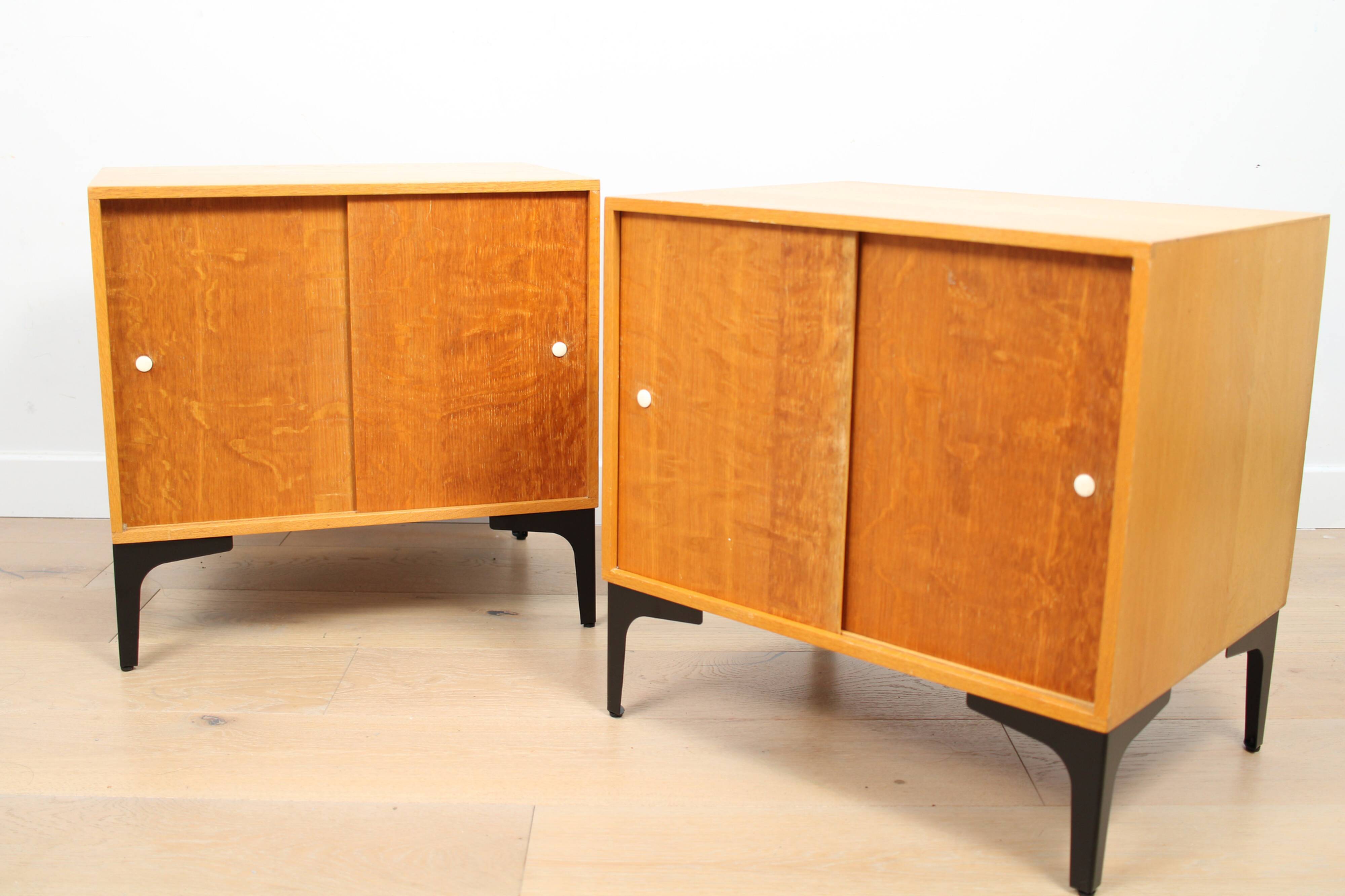 A pair of vintage mid-century bedside tables with oak sliding doors