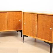 A pair of vintage mid-century bedside tables with oak sliding doors