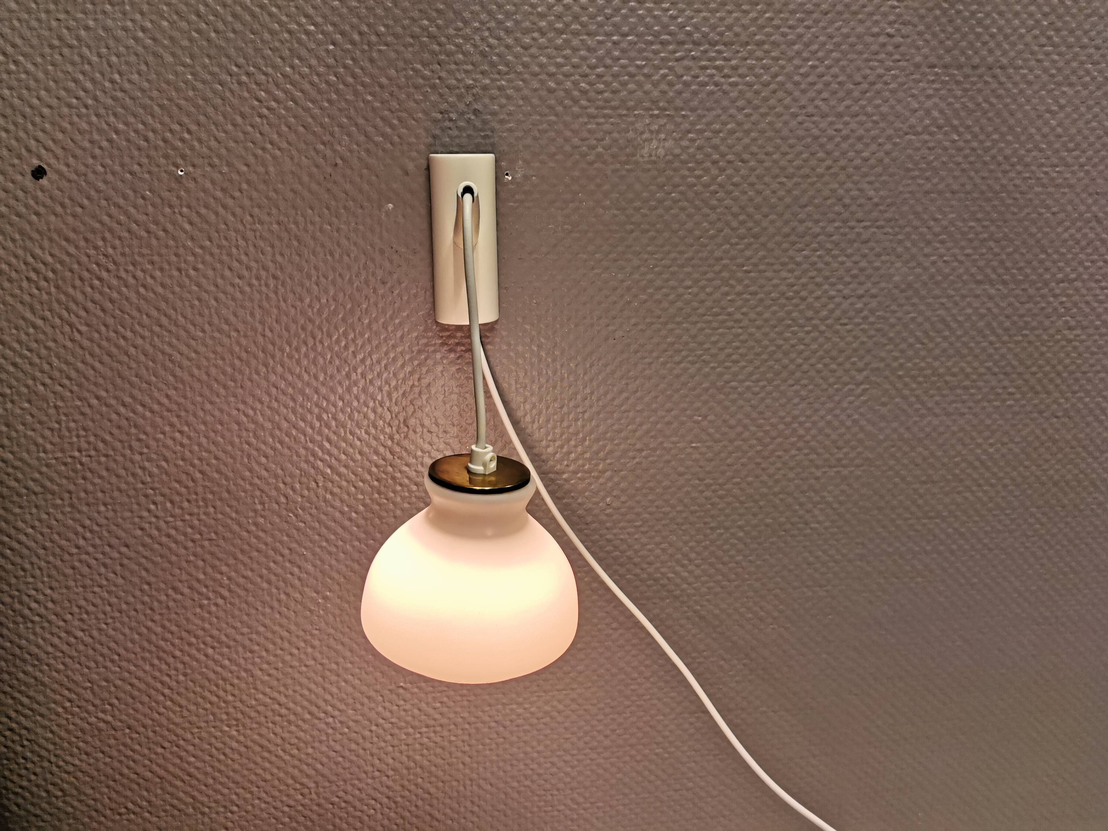 Milky white Holmegaard wall lamp with glass shade and a brass detail on top. Wooden wall bracket