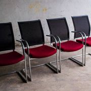 Set of 4 cantilever chairs with burgundy seat and mesh backrest.