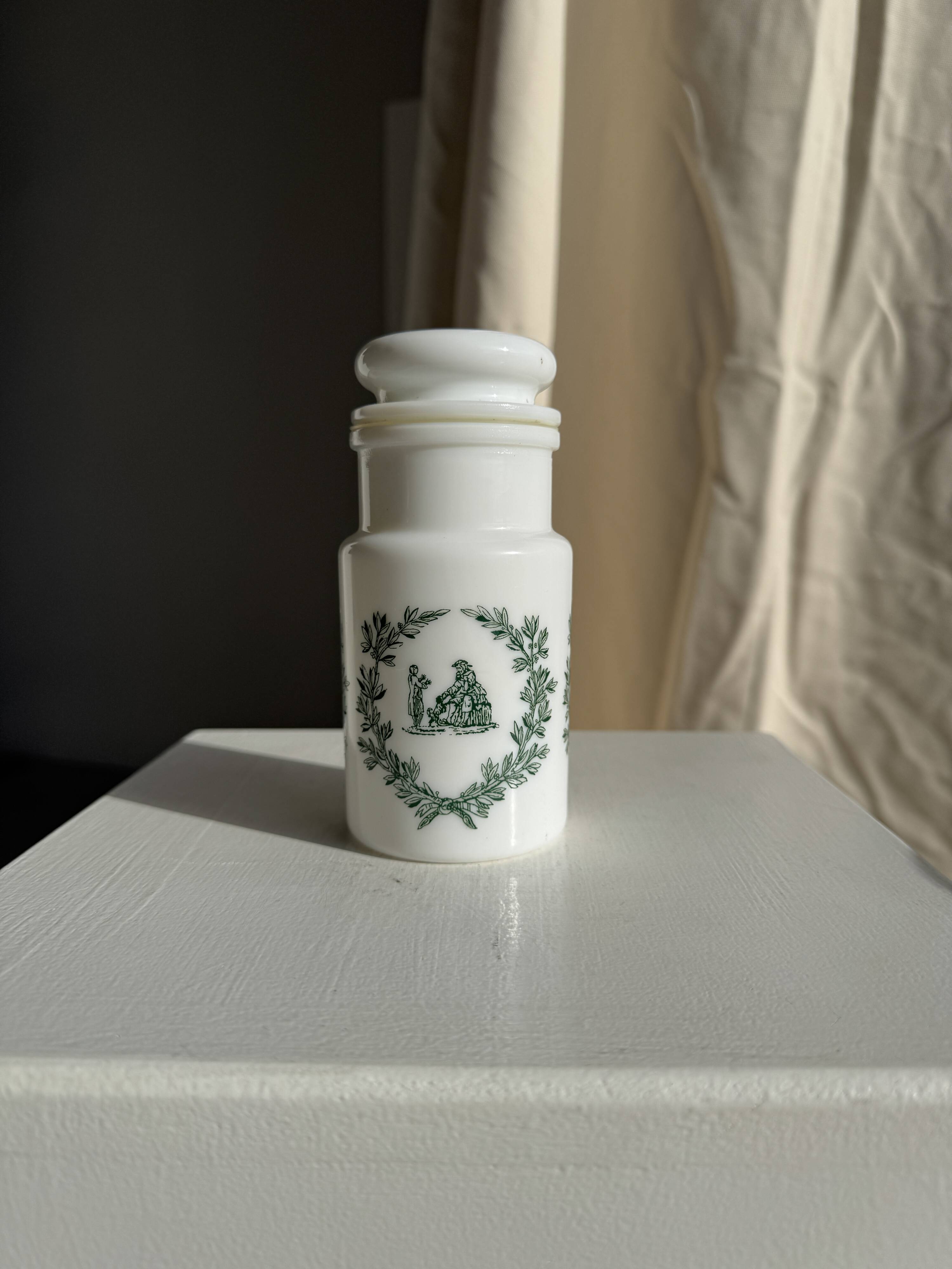 A pair of white glass bottles with Italian green patterns.