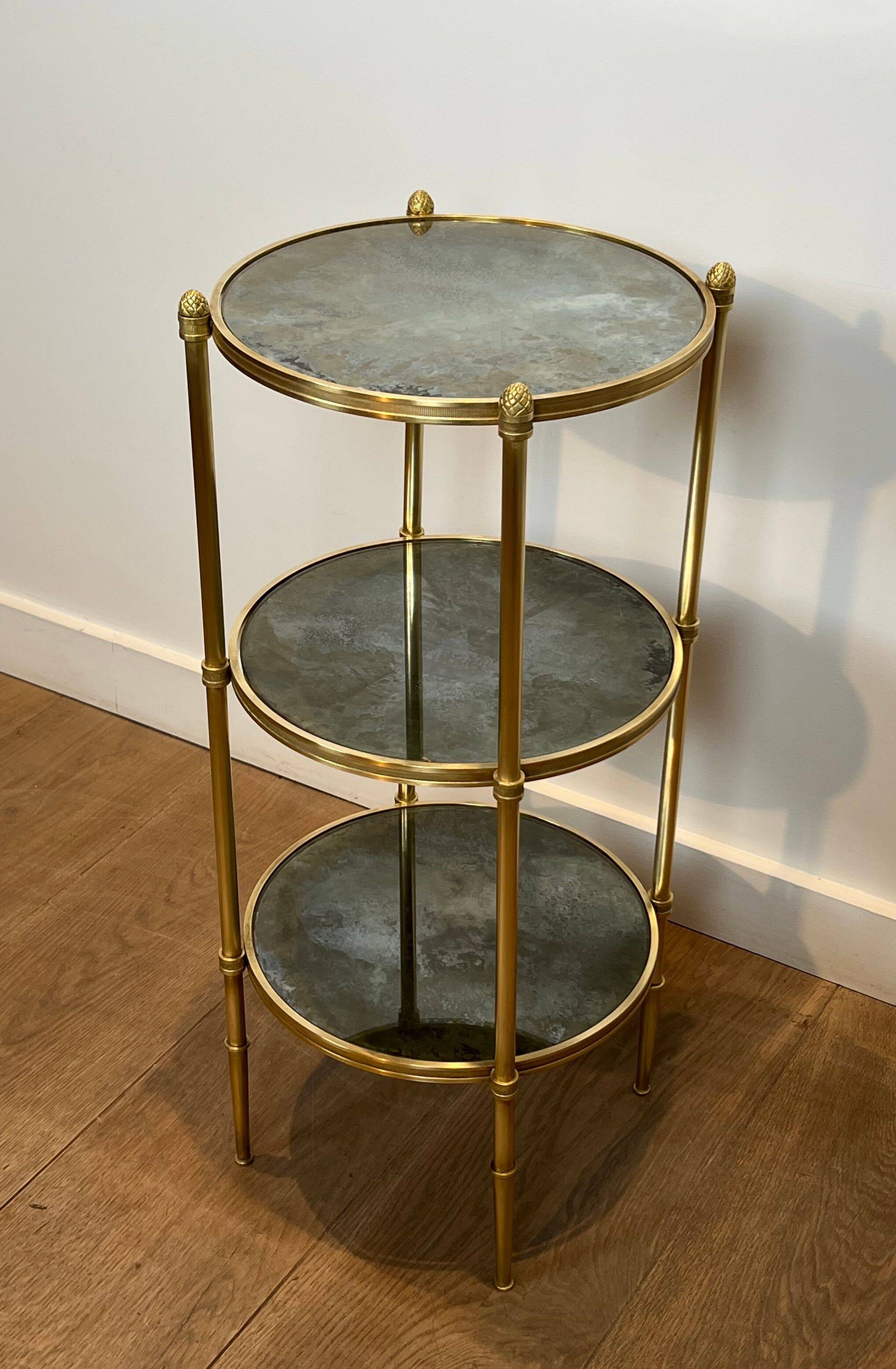Round bronze side table with triple shelves of églomisé mirrors from Maison Baguès