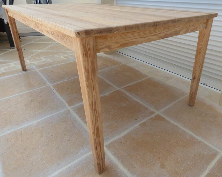 Large natural wood table with rectangular top supported by legs