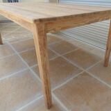 Large natural wood table with rectangular top supported by legs