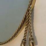 Oval brass mirror surrounded by a cord and adorned
