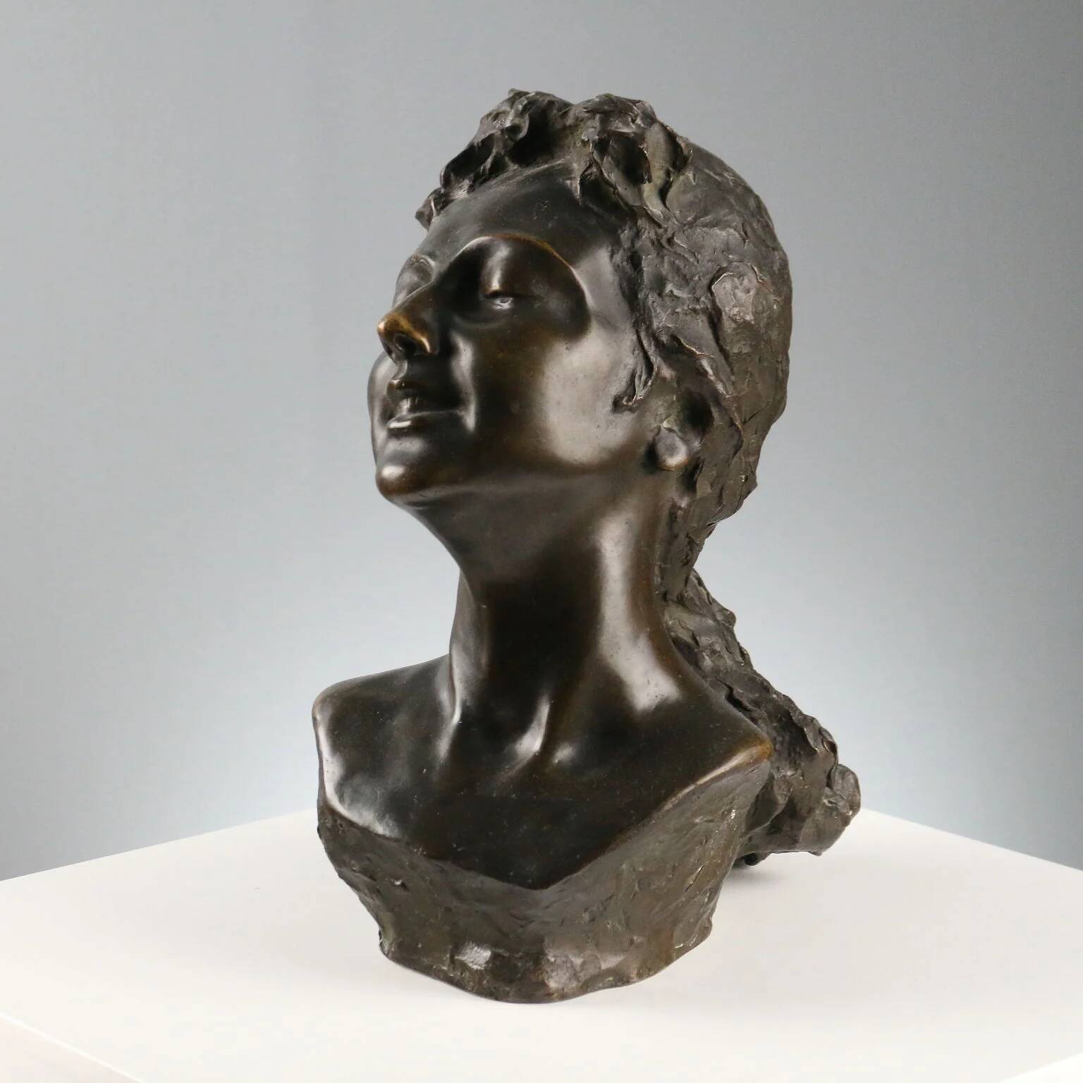 Ancient sculpture of a young woman's face in bronze, 19th-20th century.