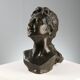 Ancient sculpture of a young woman's face in bronze, 19th-20th century.