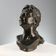 Ancient sculpture of a young woman's face in bronze, 19th-20th century.