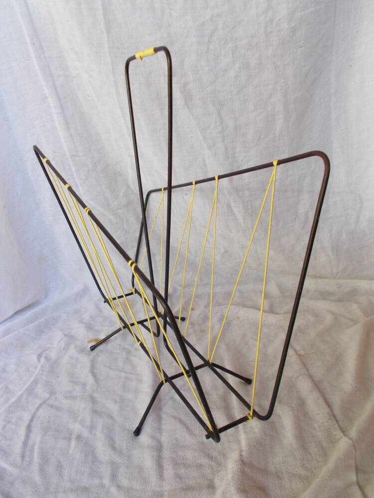 Black metal magazine rack with yellow scoubidou wire.