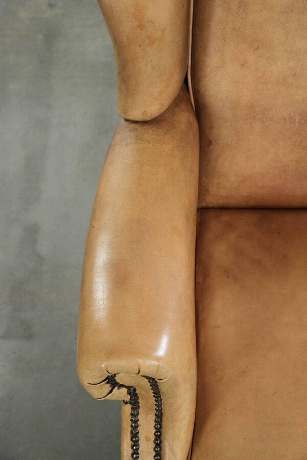 Fauteuil à oreilles en cuir de vache confortable avec un look anglais intemporel.