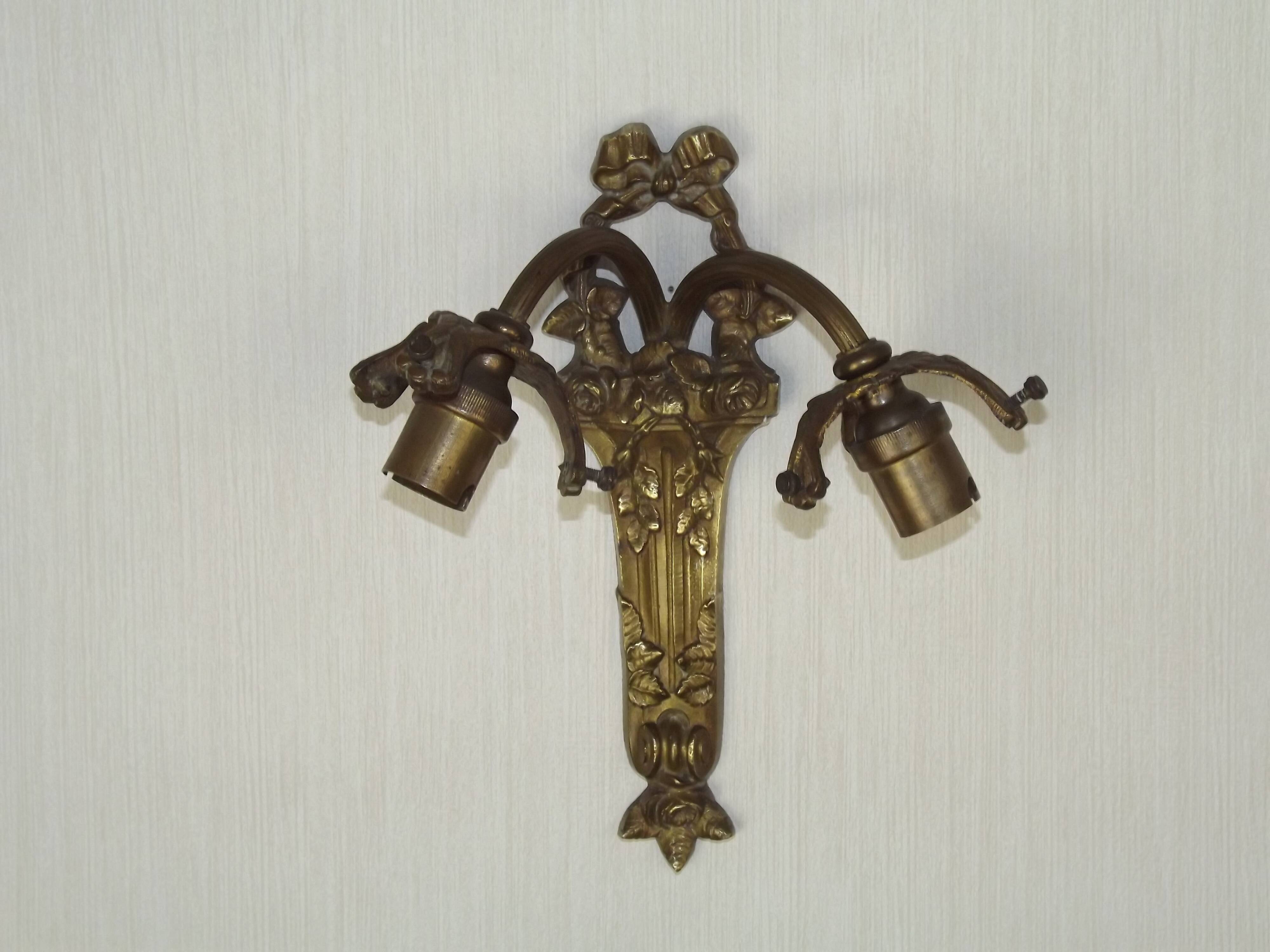 Double wall light in bronze in French Rococo style with white glass shades featuring patterns.