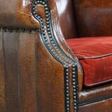 Sheep leather wingback chair with a red corduroy seat cushion and patina