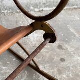 19th-century dark brown wrought-metal rocking chair with cognac leather sling seat, vintage