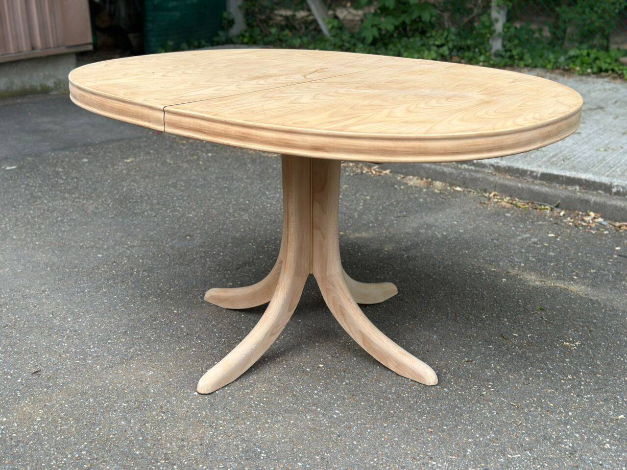 Renovated oval Scandinavian extendable dining table in wood with a central leg.