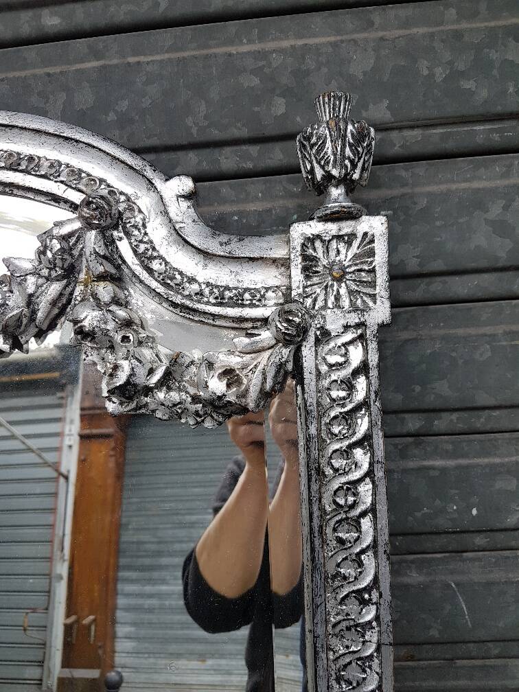 Carved and silvered wooden mirror in the Louis XVI style.