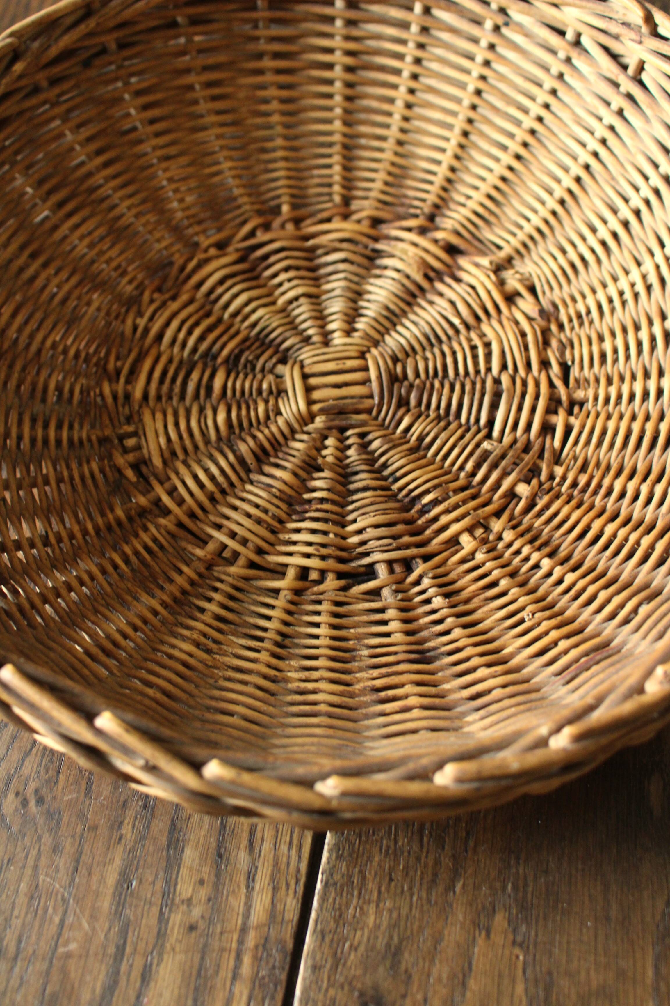 Round wicker basket with a rigid handle.
