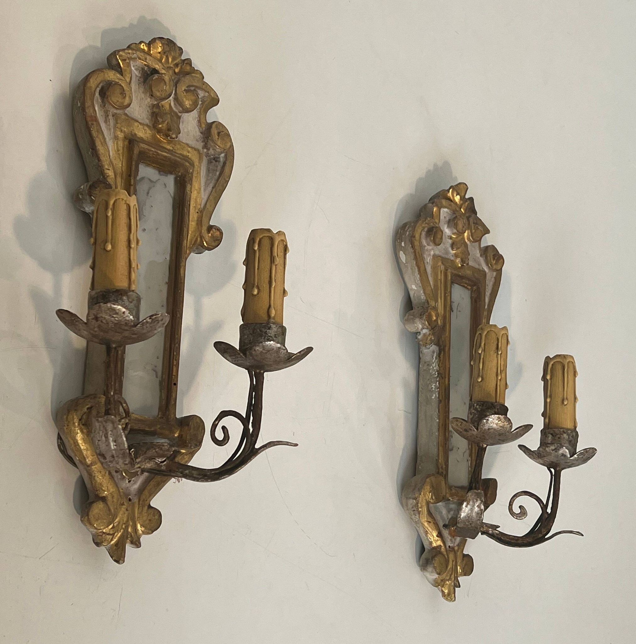 Pair of wall sconces in carved wood and silvered and gilded patinated metal with a central mirror.