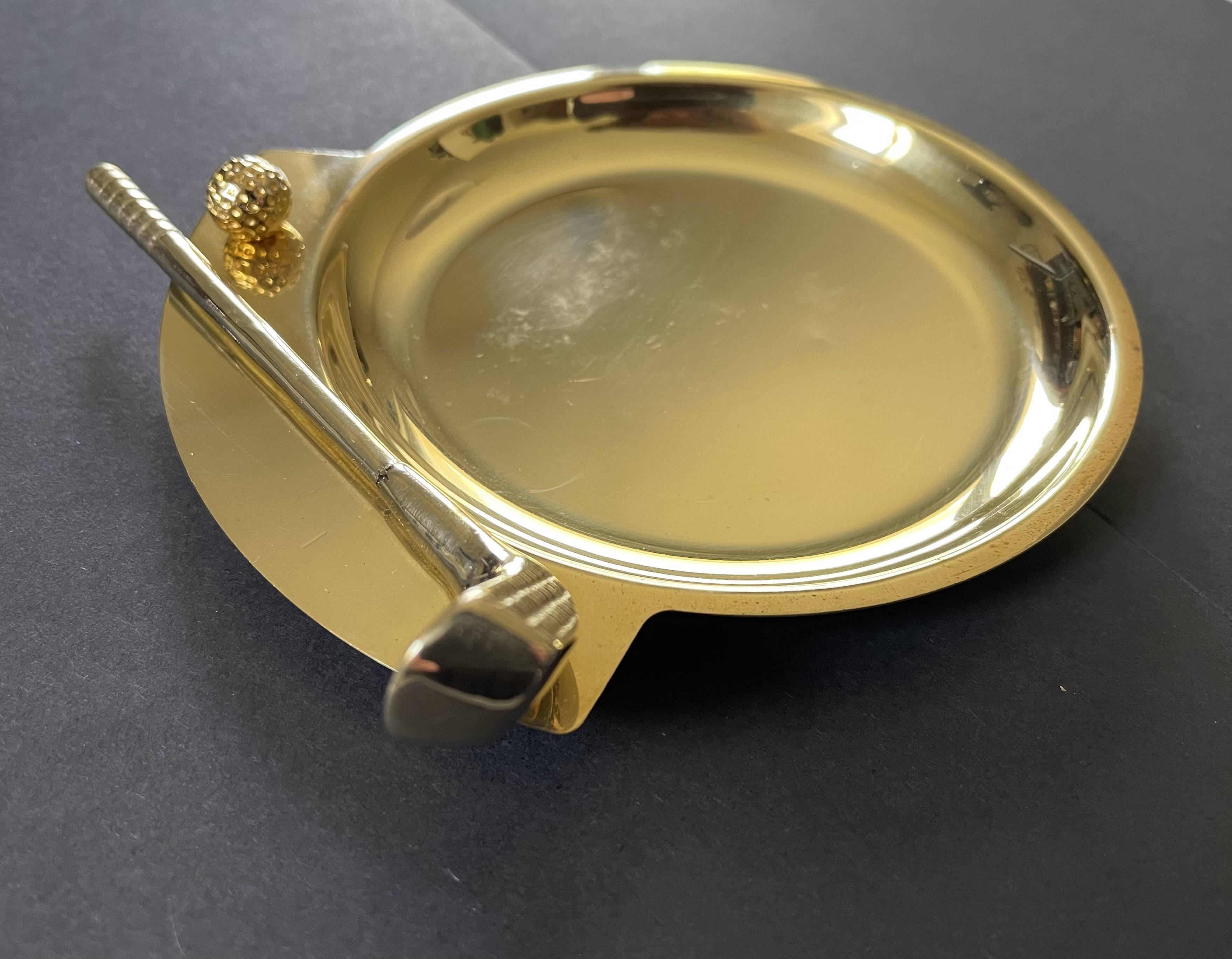 Round brass pocket tray with club and golf ball decoration.
