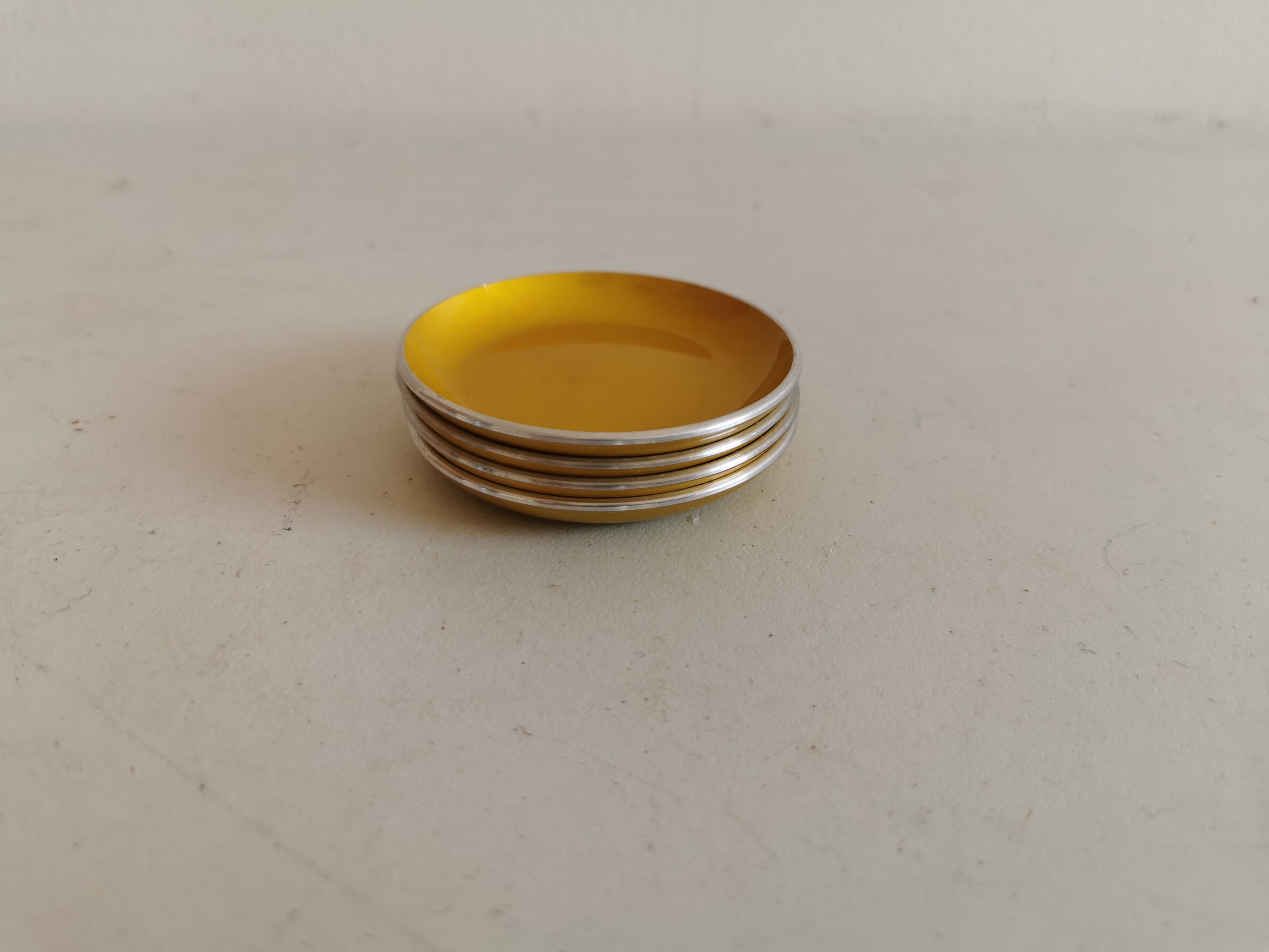 Ensemble de quatre sous-verres émaillés - cendriers de couleur jaune d’origine.