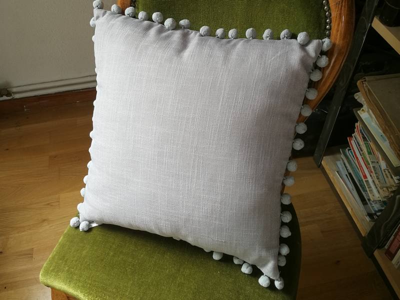 Gray cushion with pompoms