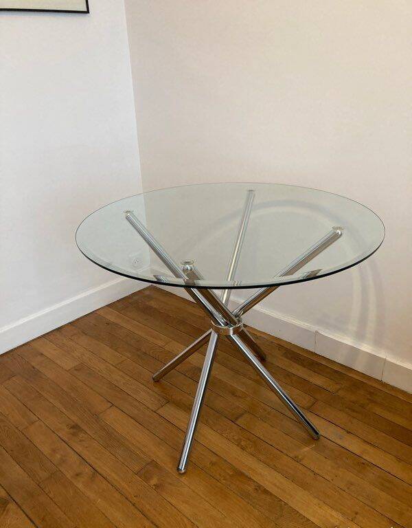 Round glass dining table with a chrome central base.