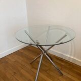 Round glass dining table with a chrome central base.