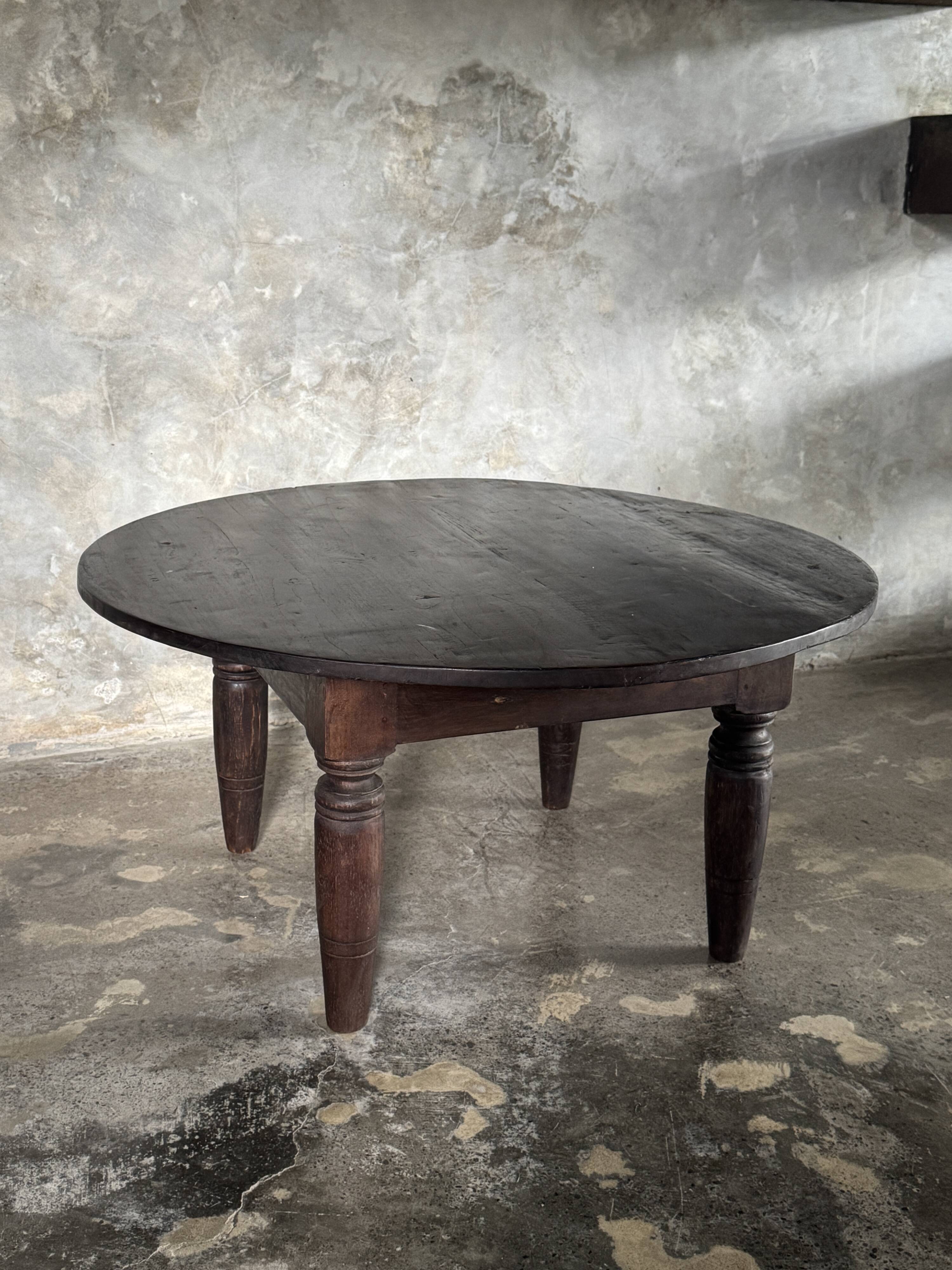 Antique round coffee table in Indonesian teak with turned legs.